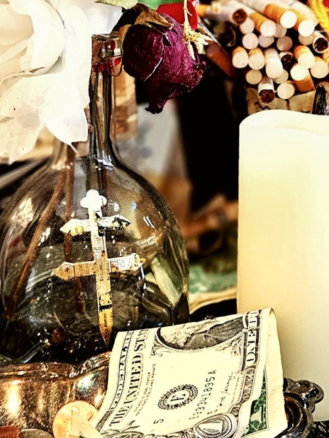 Voodoo artefacts with cross, candle, and figurine on New Orleans Haunted Ghost, Voodoo & Vampire Tour.