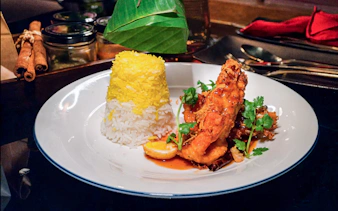 Gourmet dish with saffron rice and glazed chicken on Saffron Luxury Cruise by Banyan Tree.