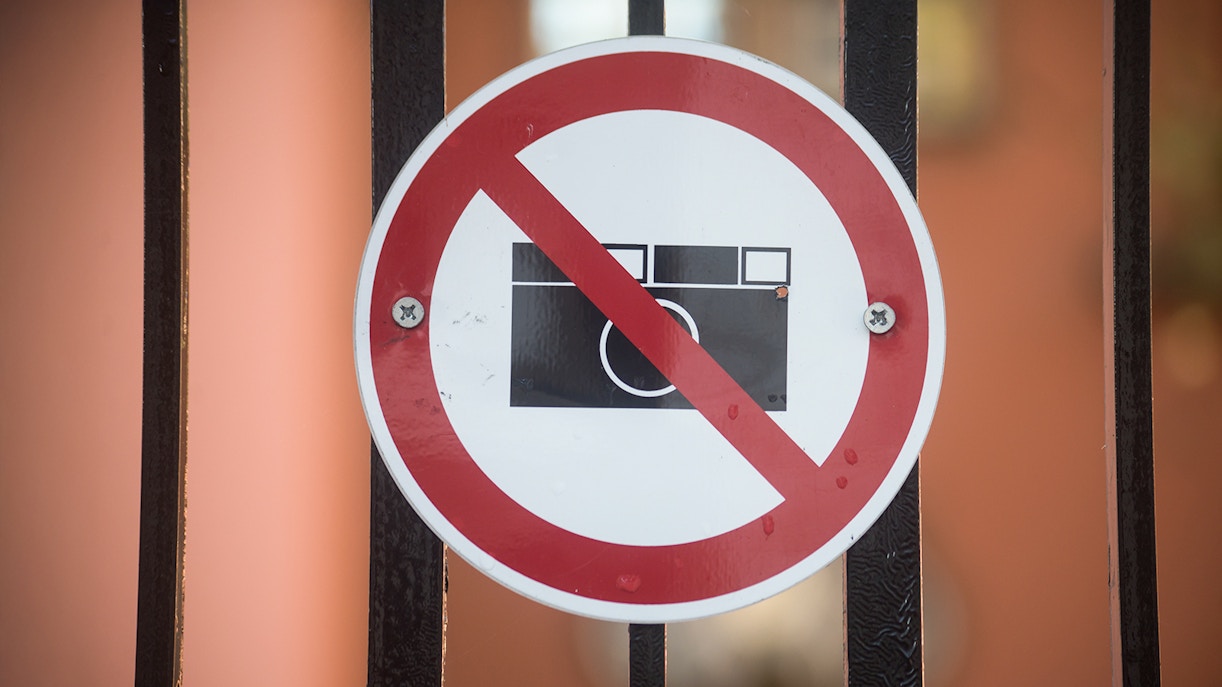 Photography prohibited signboard on a gate in a restricted area.