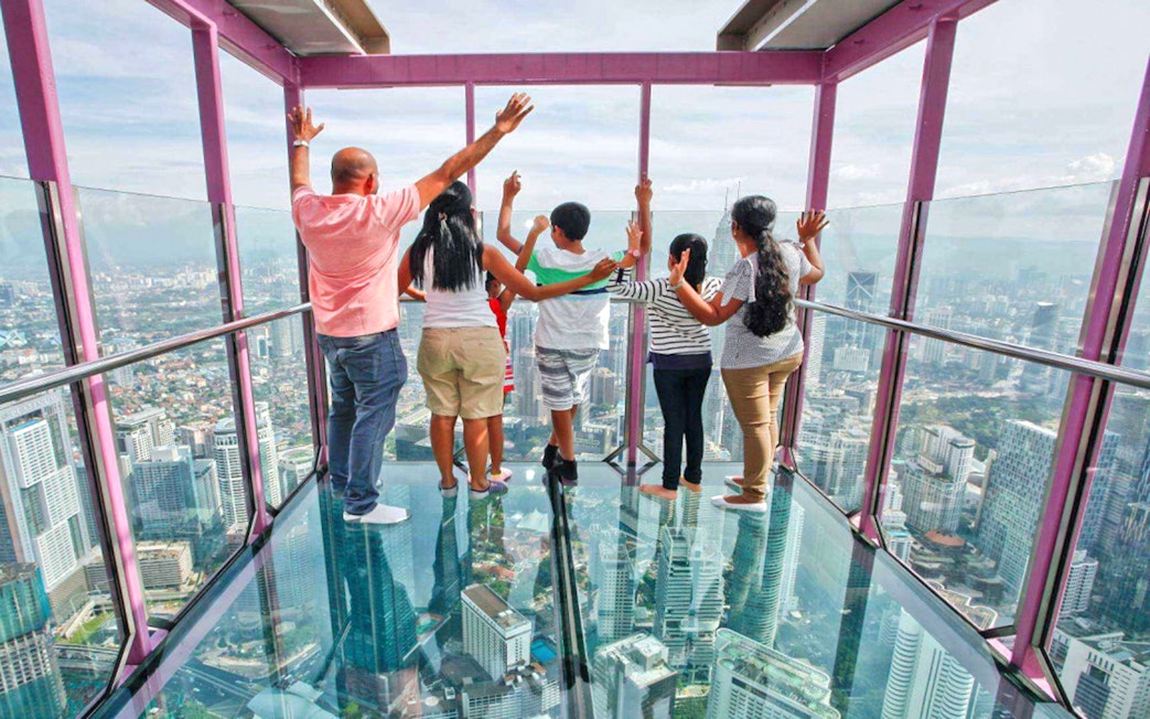 Visitors enjoying panoramic views from KL Tower's glass observation deck in Kuala Lumpur.