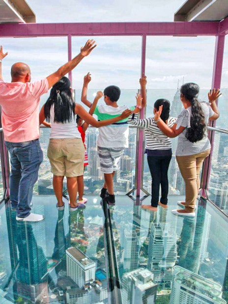 Visitors enjoying panoramic views from KL Tower's glass observation deck in Kuala Lumpur.