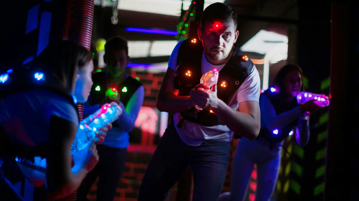 Visitors engaging in a lasertag game with glowing vests and laser guns.