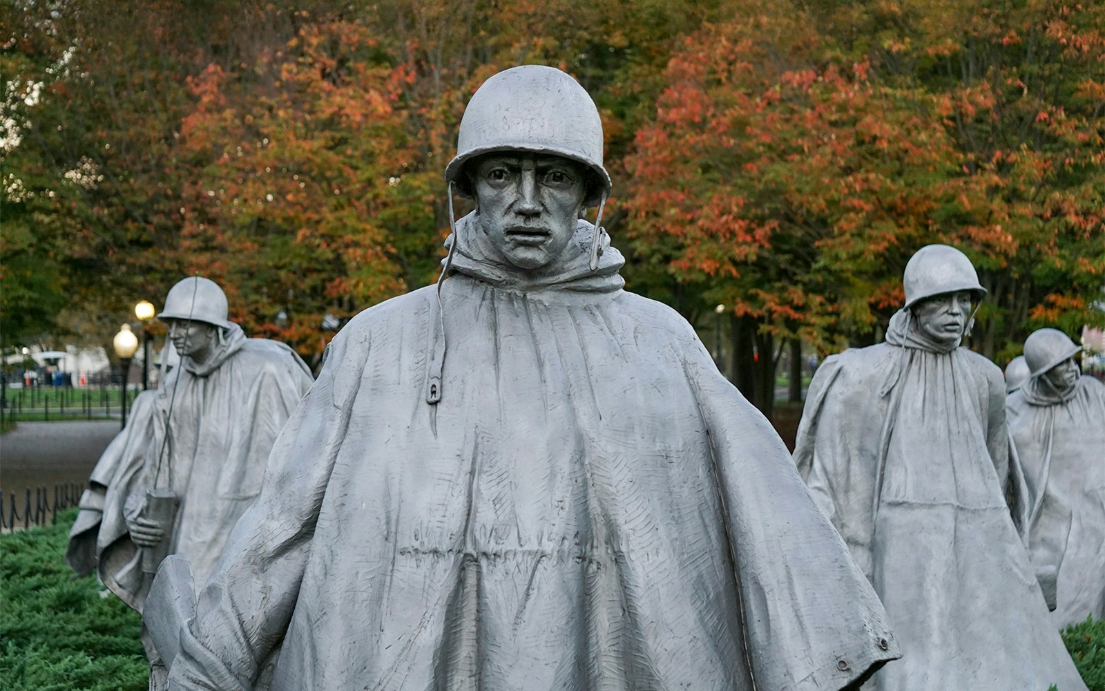 Statues of US servicemen at the Korean War Memorial, Washington, DC, with autumn trees in background.