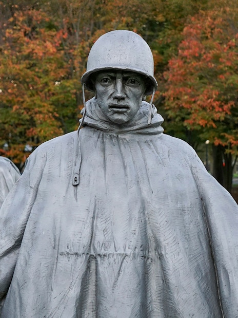 Statues of US servicemen at the Korean War Memorial, Washington, DC, with autumn trees in background.