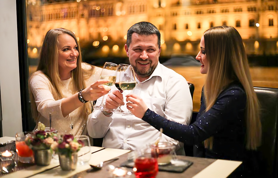 Guests toasting on a Budapest New Year's Eve cruise on the Danube with drinks.
