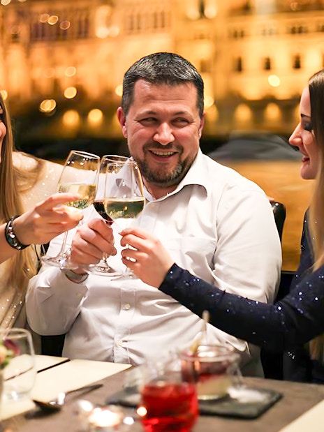 Guests toasting on a Budapest New Year's Eve cruise on the Danube with drinks.
