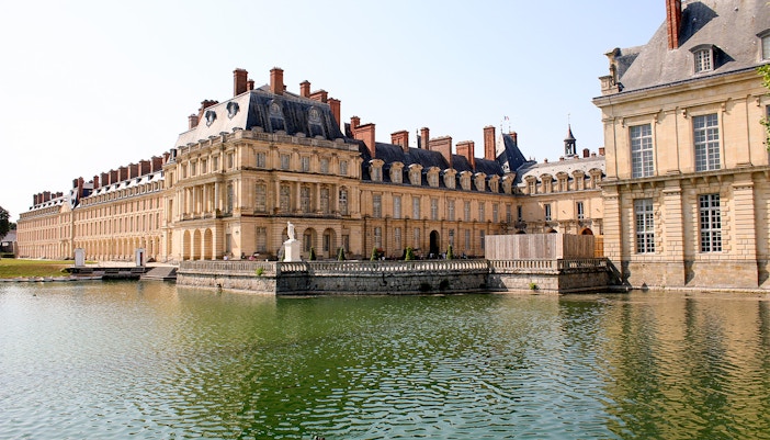 Château de Fontainebleau exterior with grand entrance and lush gardens in Fontainebleau, France.