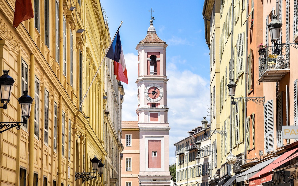 Clock tower on Rue Saint-François de Paule, Nice, France, with French flag.