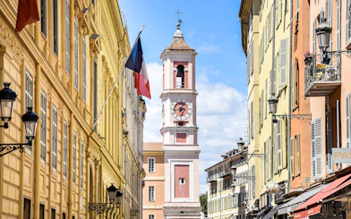 Clock tower on Rue Saint-François de Paule, Nice, France, with French flag.