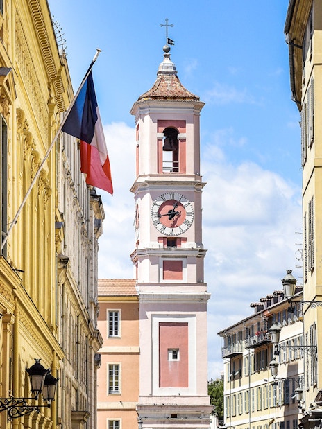 Clock tower on Rue Saint-François de Paule, Nice, France, with French flag.