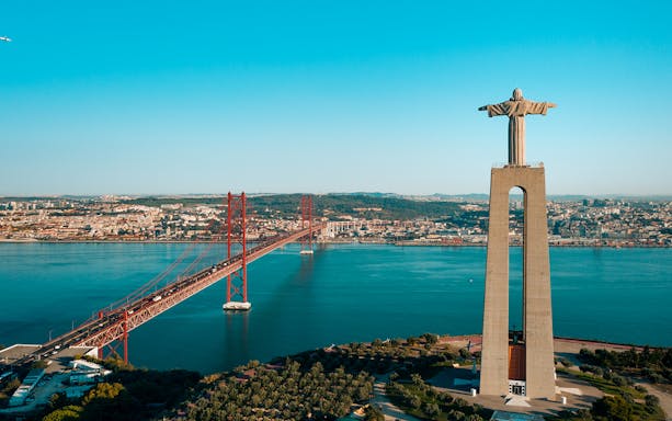 Helicopter view of Lisbon's Christ the King statue and 25 de Abril Bridge.