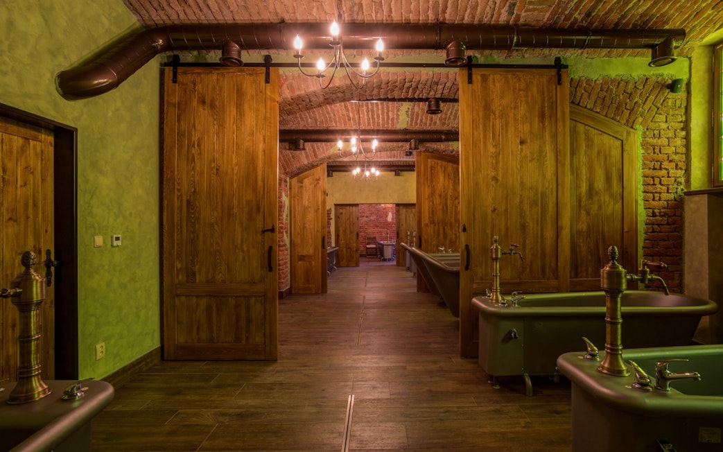 Spa bath tubs in a rustic room with wooden doors and brick walls.