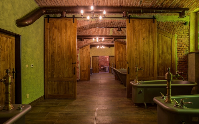 Spa bath tubs in a rustic room with wooden doors and brick walls.