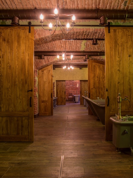 Spa bath tubs in a rustic room with wooden doors and brick walls.