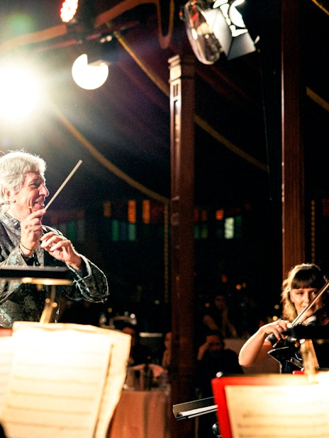 Conductor leading orchestra at Strauss concert in Prater Vienna.