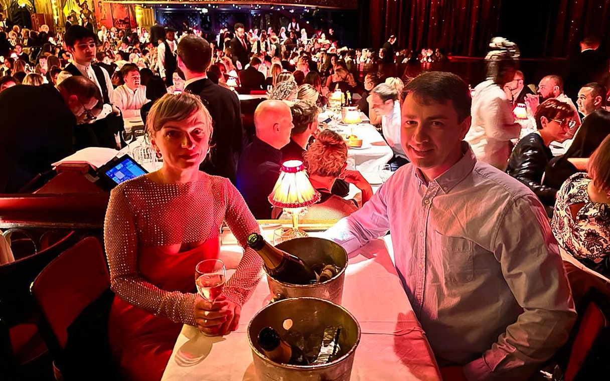 Couple enjoying champagne at a table during the Moulin Rouge show in Paris.