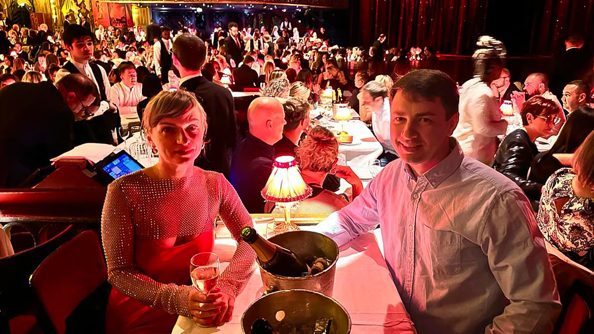 Couple enjoying champagne at a table during the Moulin Rouge show in Paris.