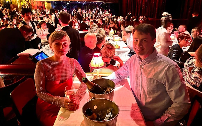 Couple enjoying champagne at a table during the Moulin Rouge show in Paris.