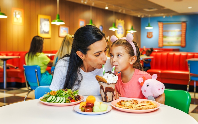 Mother and daughter sharing milkshake at Peppa Pig Theme Park, Florida.