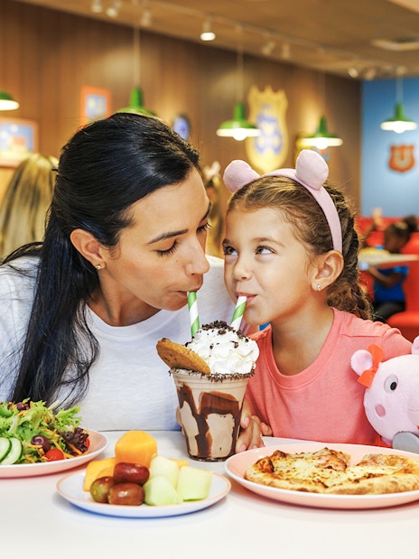 Mother and daughter sharing milkshake at Peppa Pig Theme Park, Florida.