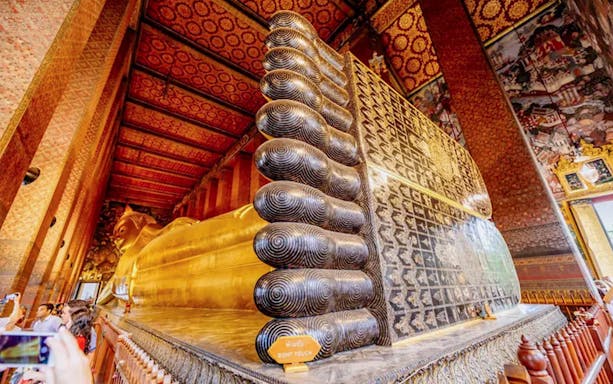 Reclining Buddha statue at Wat Phra Chetuphon, Bangkok, with intricate foot details.
