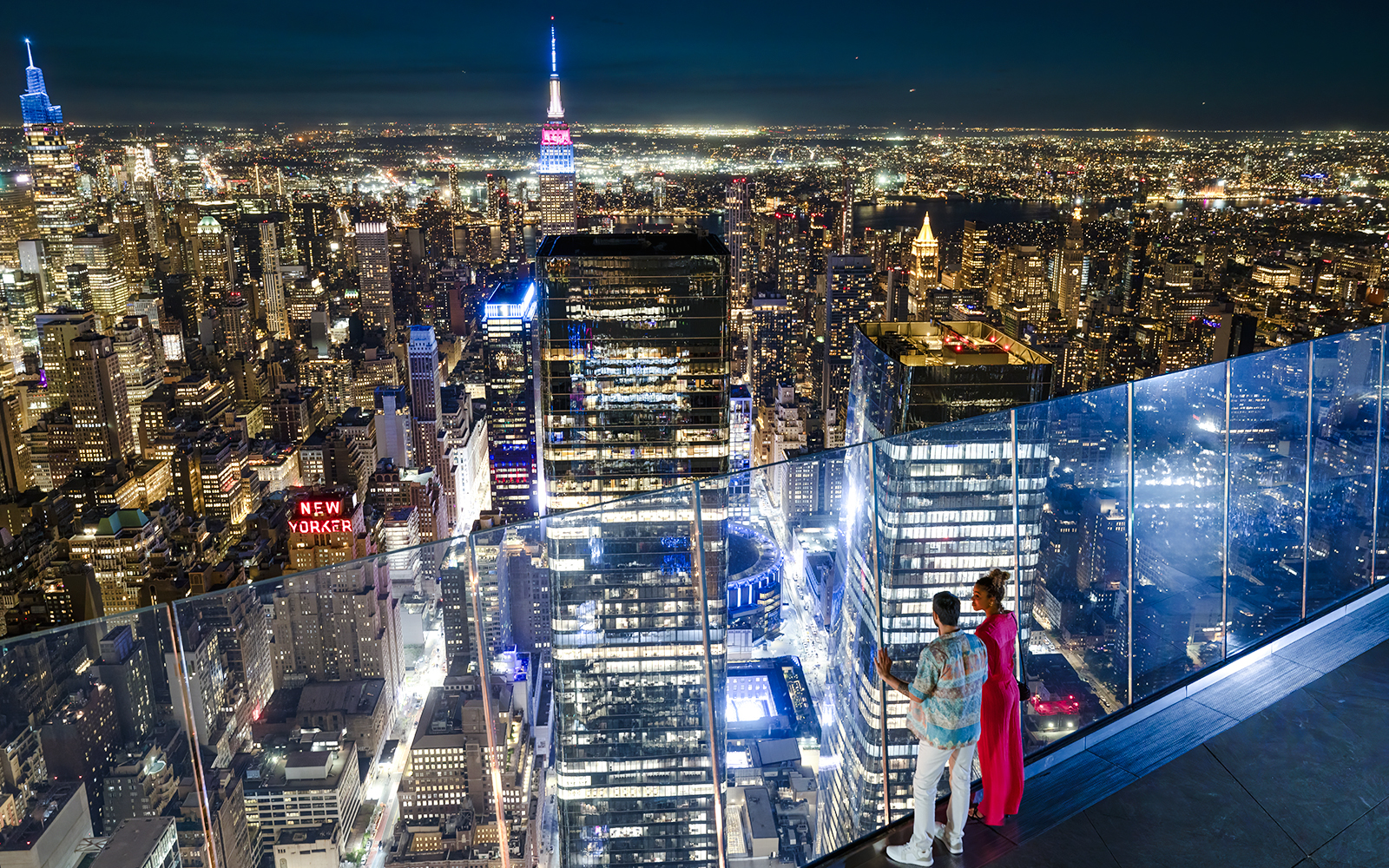 Couple enjoying New York City skyline from Edge observation deck at night.