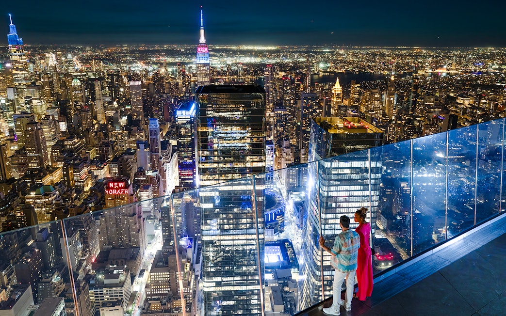 Couple enjoying New York City skyline from Edge observation deck at night.