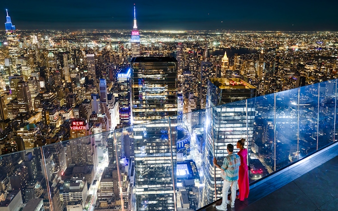 Couple enjoying New York City skyline from Edge observation deck at night.