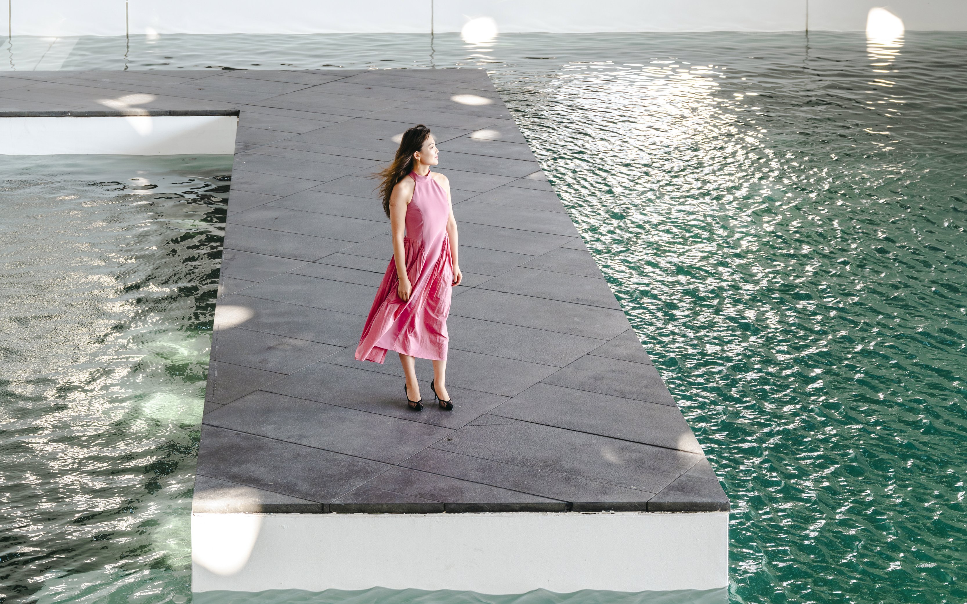 Person standing on a platform by water at Louvre Abu Dhabi.