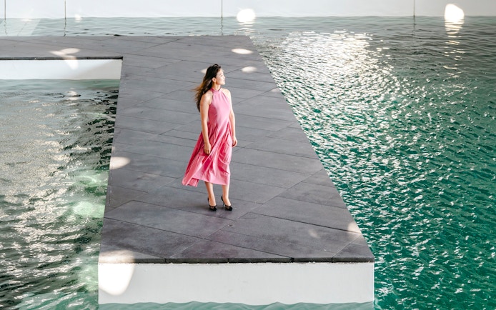 Person standing on a platform by water at Louvre Abu Dhabi.