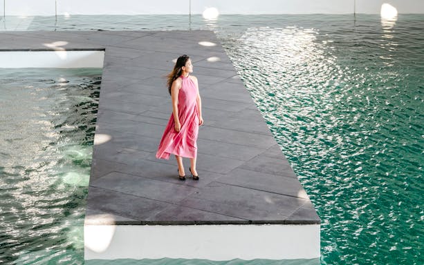 Person standing on a platform by water at Louvre Abu Dhabi.