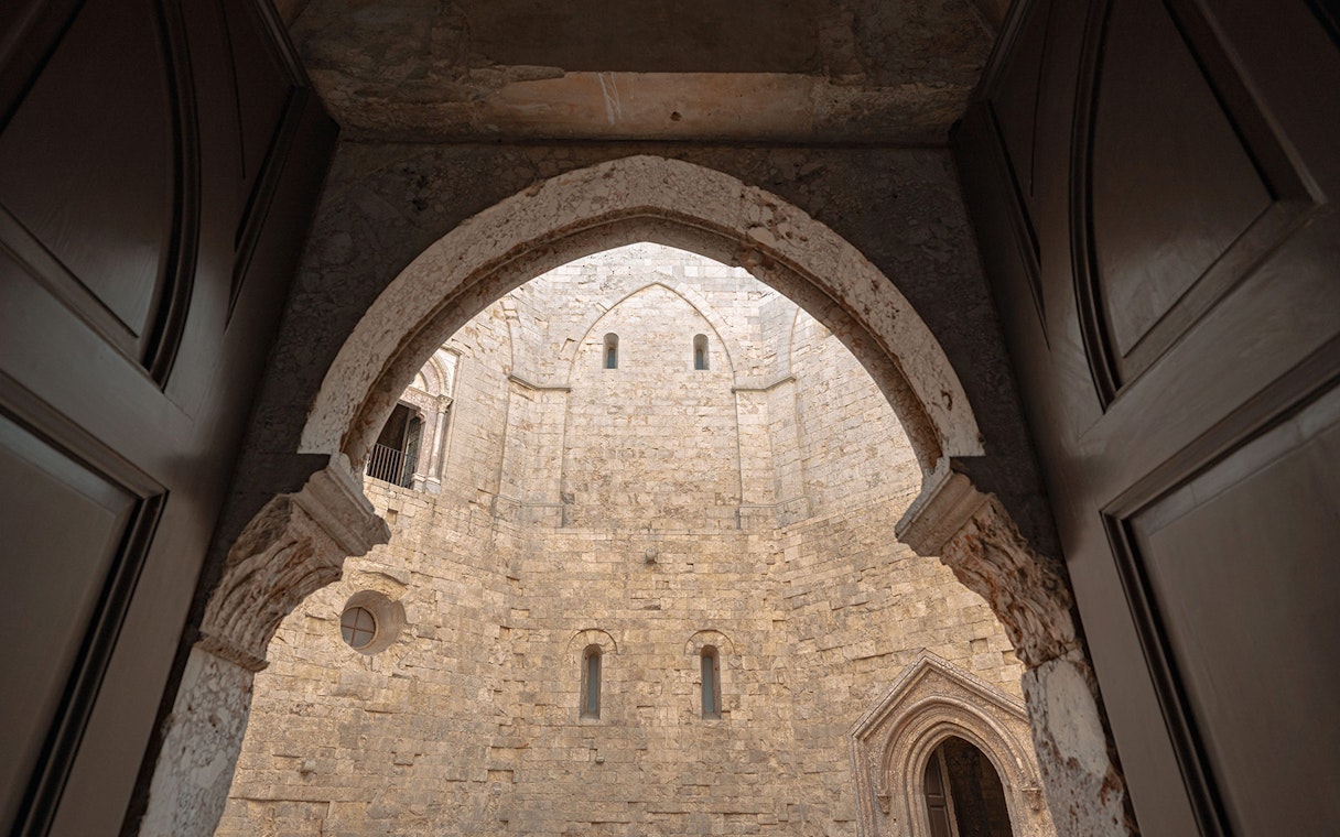 View of Castel del Monte's stone courtyard through an arched doorway, Italy.
