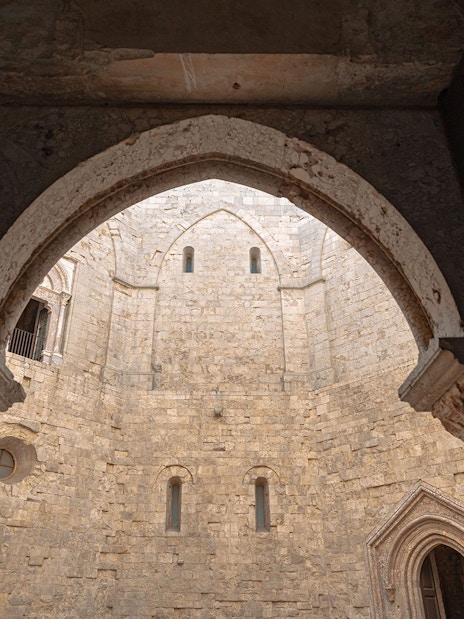 View of Castel del Monte's stone courtyard through an arched doorway, Italy.