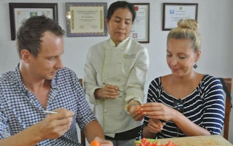 Thai carving class with master carver guiding students on fruit and vegetable techniques.