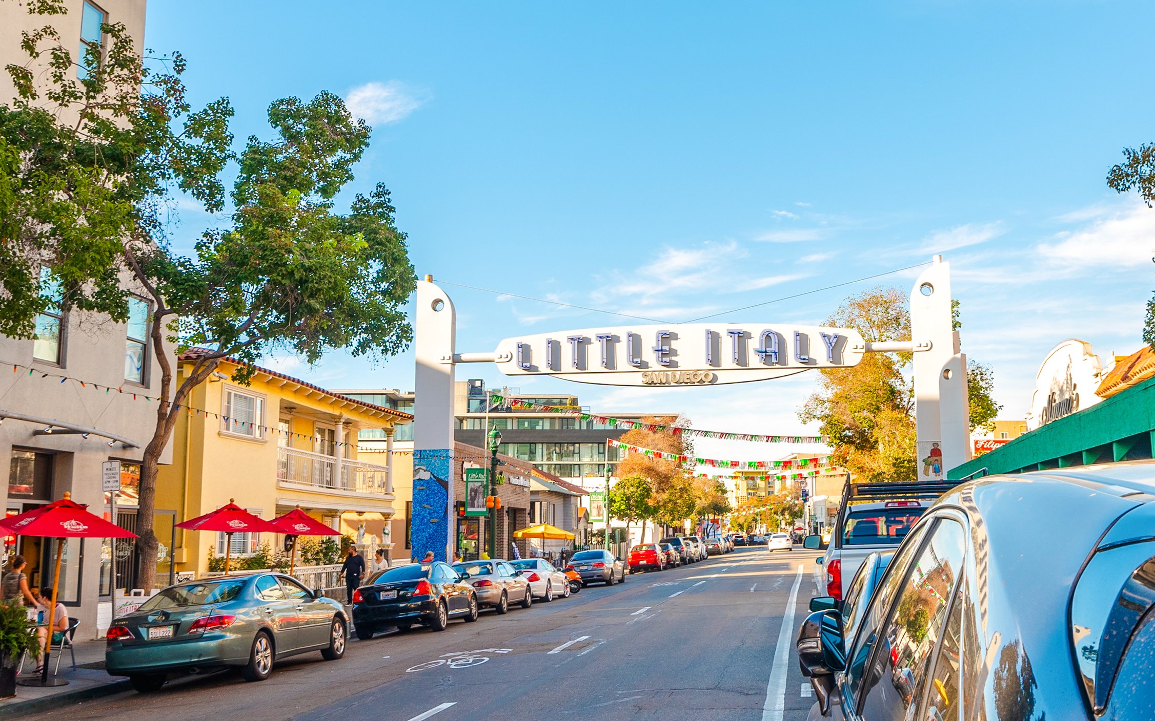 Little Italy sign over a street with cars and buildings in San Diego.