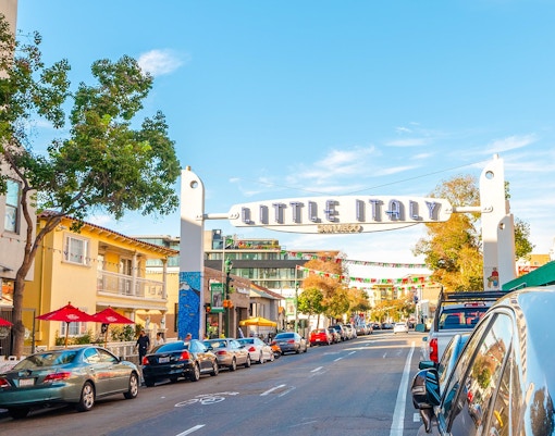 Little Italy sign over a street with cars and buildings in San Diego.