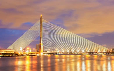 Rama VIII Bridge illuminated at night over the Chao Phraya River in Bangkok, Thailand.