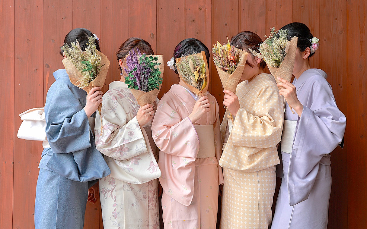 Women in kimonos holding bouquets in Gion, Kyoto.