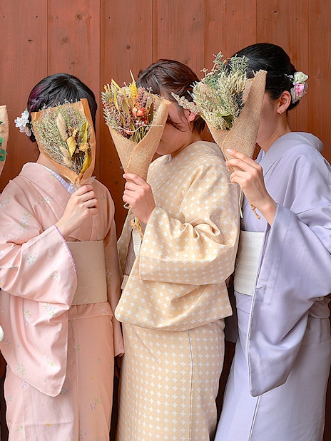 Women in kimonos holding bouquets in Gion, Kyoto.