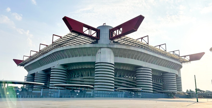 San Siro Stadium exterior in Milan, Italy, with distinctive red roof structures.