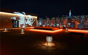 Rooftop view of DRUM TAO Theater Kyoto with illuminated lanterns and city skyline.