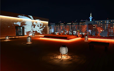 Rooftop view of DRUM TAO Theater Kyoto with illuminated lanterns and city skyline.