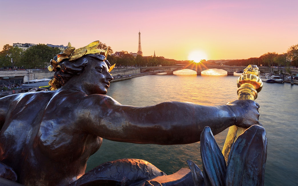 Statue on Pont Alexandre III with Eiffel Tower and sunset in Paris.