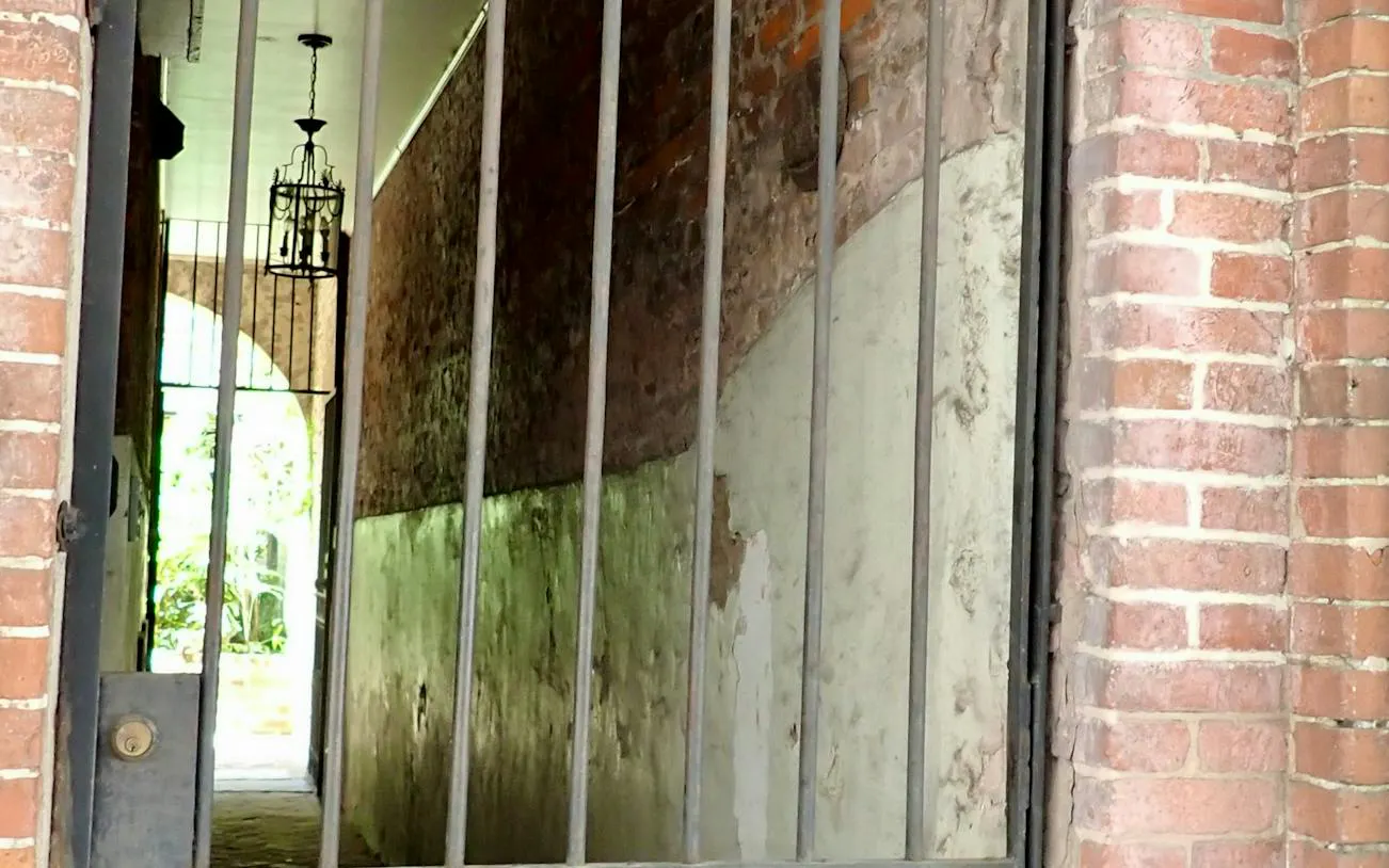 Gated brick alleyway with hanging lantern in New Orleans, part of self-guided city exploration game.