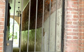 Gated brick alleyway with hanging lantern in New Orleans, part of self-guided city exploration game.