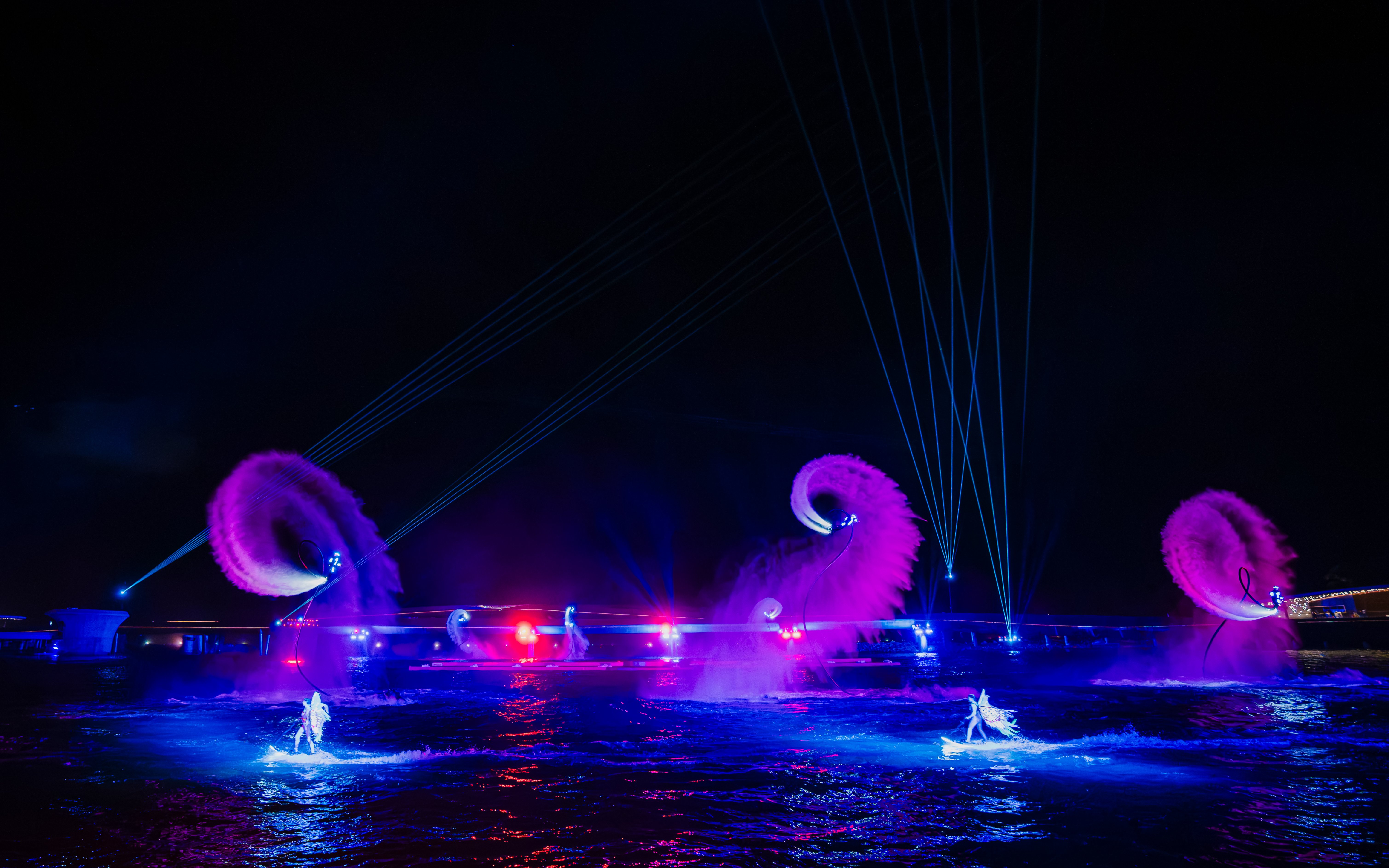 Performers on water with colorful lights and fountains at Symphony of the Sea show.