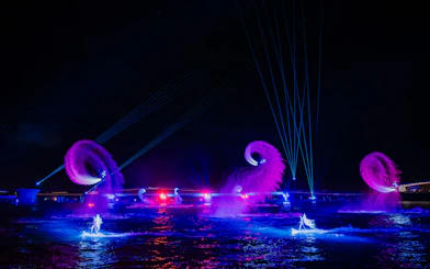 Performers on water with colorful lights and fountains at Symphony of the Sea show.