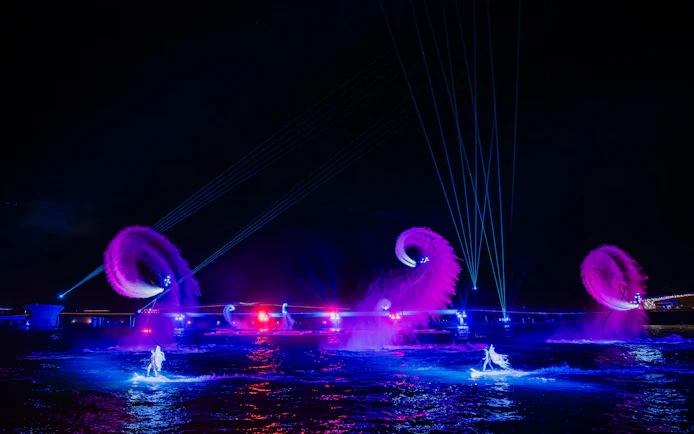 Performers on water with colorful lights and fountains at Symphony of the Sea show.