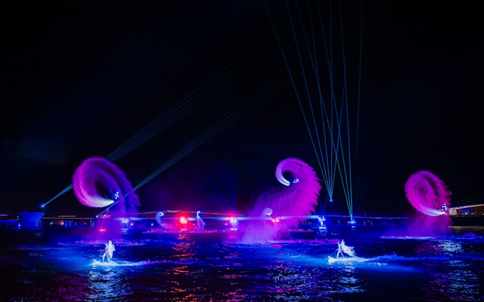 Performers on water with colorful lights and fountains at Symphony of the Sea show.