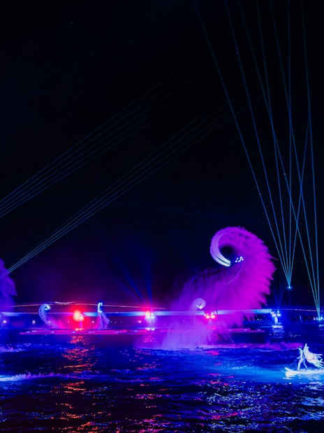 Performers on water with colorful lights and fountains at Symphony of the Sea show.